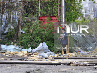 A woman is holding a dog and standing among the rubble near a Nova Poshta depot and cargo branch that has been damaged by a Russian ballisti...