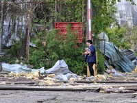 A woman is holding a dog and standing among the rubble near a Nova Poshta depot and cargo branch that has been damaged by a Russian ballisti...