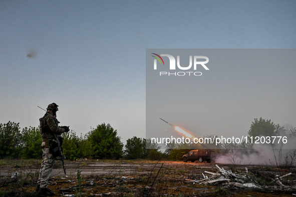 A serviceman from the Steppe Wolves all-volunteer unit is standing near a pickup equipped with Grad rocket launch tubes, which were captured...