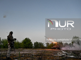 A serviceman from the Steppe Wolves all-volunteer unit is standing near a pickup equipped with Grad rocket launch tubes, which were captured...