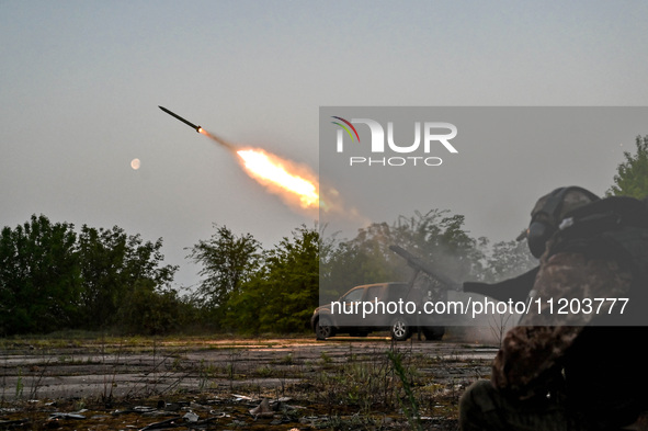 A serviceman from the Steppe Wolves all-volunteer unit is standing near a pickup equipped with Grad rocket launch tubes, which were captured...