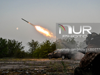 A serviceman from the Steppe Wolves all-volunteer unit is standing near a pickup equipped with Grad rocket launch tubes, which were captured...