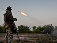 A serviceman from the Steppe Wolves all-volunteer unit is standing near a pickup equipped with Grad rocket launch tubes, which were captured...