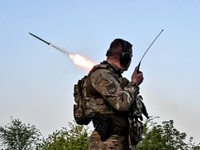 A serviceman from the Steppe Wolves all-volunteer unit is standing near a pickup equipped with Grad rocket launch tubes, which were captured...