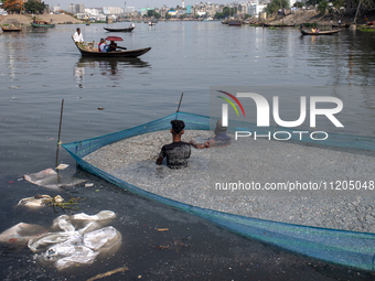 Laborers are cleaning plastic chips on the bank of the Buriganga River while passengers are crossing the river by boat in Dhaka, Bangladesh,...