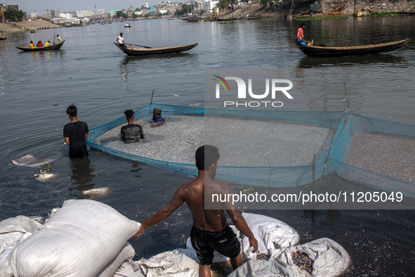 Laborers are cleaning plastic chips on the bank of the Buriganga River while passengers are crossing the river by boat in Dhaka, Bangladesh,...