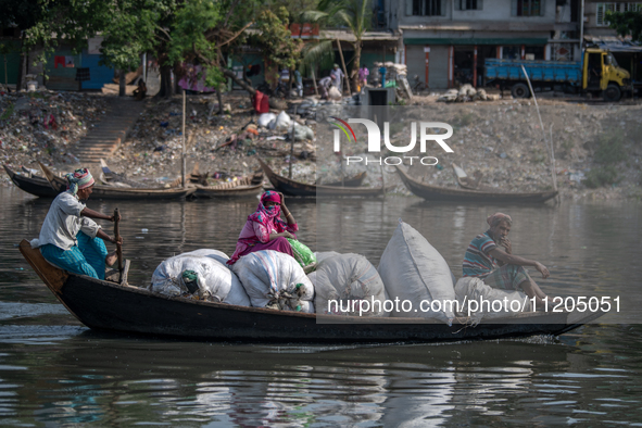 Passengers are reacting to the camera as they carry plastic on a boat to a plastic recycling factory in Dhaka, Bangladesh, on May 2, 2024. T...