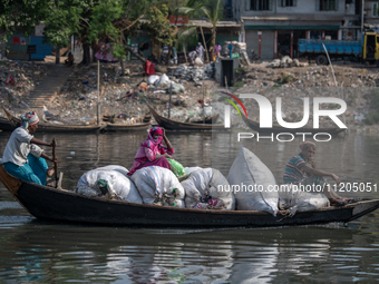 Passengers are reacting to the camera as they carry plastic on a boat to a plastic recycling factory in Dhaka, Bangladesh, on May 2, 2024. T...