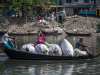 Passengers are reacting to the camera as they carry plastic on a boat to a plastic recycling factory in Dhaka, Bangladesh, on May 2, 2024. T...