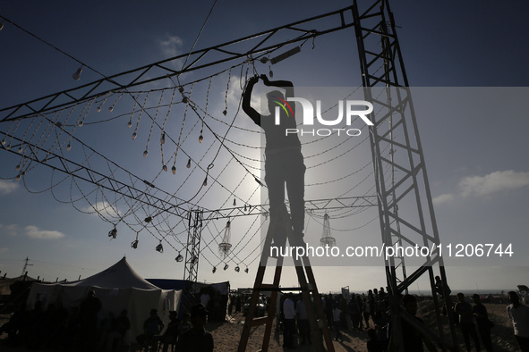 A man is embracing decorative lighting ahead of a mass wedding ceremony in Khan Yunis, in the southern Gaza Strip, on May 3, 2024, amid the...