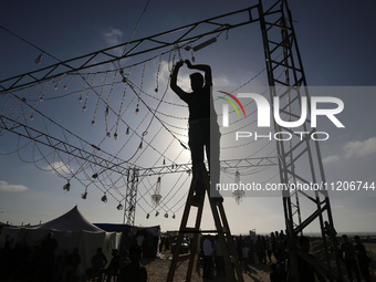 A man is embracing decorative lighting ahead of a mass wedding ceremony in Khan Yunis, in the southern Gaza Strip, on May 3, 2024, amid the...