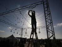 A man is embracing decorative lighting ahead of a mass wedding ceremony in Khan Yunis, in the southern Gaza Strip, on May 3, 2024, amid the...