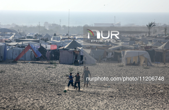 Displaced Palestinians are playing football next to their tents in Khan Younis, in the southern Gaza Strip, on May 3, 2024, amid the ongoing...