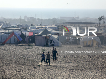 Displaced Palestinians are playing football next to their tents in Khan Younis, in the southern Gaza Strip, on May 3, 2024, amid the ongoing...