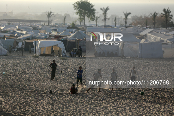 Displaced Palestinians are playing football next to their tents in Khan Younis, in the southern Gaza Strip, on May 3, 2024, amid the ongoing...