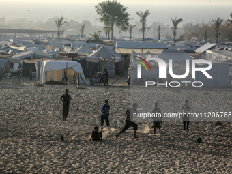 Displaced Palestinians are playing football next to their tents in Khan Younis, in the southern Gaza Strip, on May 3, 2024, amid the ongoing...