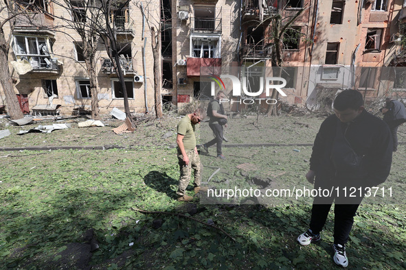 People are standing outside an apartment block that has been damaged by Russian shelling in Kharkiv, northeastern Ukraine, on May 5, 2024. N...