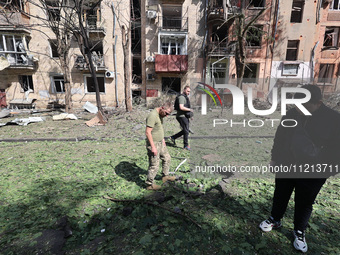 People are standing outside an apartment block that has been damaged by Russian shelling in Kharkiv, northeastern Ukraine, on May 5, 2024. N...