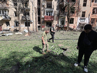 People are standing outside an apartment block that has been damaged by Russian shelling in Kharkiv, northeastern Ukraine, on May 5, 2024. N...