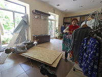 A woman is arranging blouses on the rack in a clothing shop that was damaged by Russian shelling in Kharkiv, Ukraine, on May 5, 2024. (