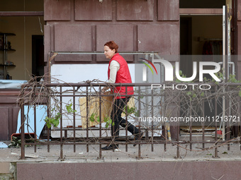 A woman is standing outside a building that has been damaged by Russian shelling in Kharkiv, Ukraine, on May 5, 2024. (