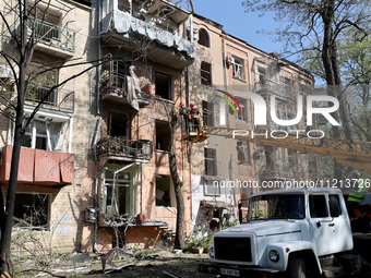 Municipal workers are cutting down a tree outside an apartment block that was damaged by Russian shelling in Kharkiv, northeastern Ukraine,...