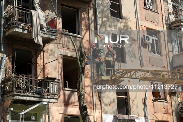 Municipal workers are cutting down a tree outside an apartment block that was damaged by Russian shelling in Kharkiv, northeastern Ukraine,...