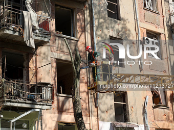 Municipal workers are cutting down a tree outside an apartment block that was damaged by Russian shelling in Kharkiv, northeastern Ukraine,...