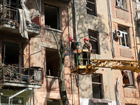 Municipal workers are cutting down a tree outside an apartment block that was damaged by Russian shelling in Kharkiv, northeastern Ukraine,...