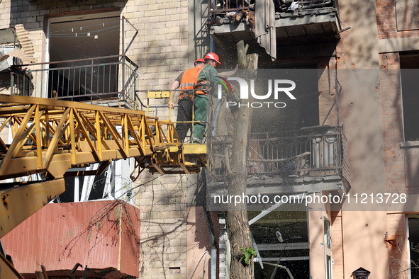 Municipal workers are cutting down a tree outside an apartment block that was damaged by Russian shelling in Kharkiv, northeastern Ukraine,...