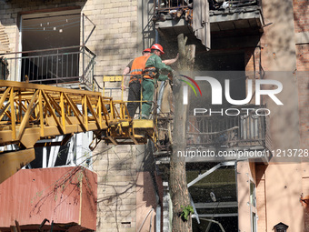 Municipal workers are cutting down a tree outside an apartment block that was damaged by Russian shelling in Kharkiv, northeastern Ukraine,...