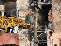 Municipal workers are cutting down a tree outside an apartment block that was damaged by Russian shelling in Kharkiv, northeastern Ukraine,...