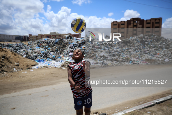 A Palestinian boy is playing next to piles of garbage amid the ongoing conflict in Gaza between Israel and Hamas in Deir Al-Balah, in the ce...