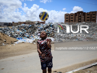 A Palestinian boy is playing next to piles of garbage amid the ongoing conflict in Gaza between Israel and Hamas in Deir Al-Balah, in the ce...