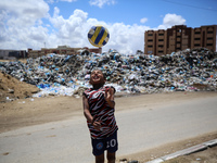 A Palestinian boy is playing next to piles of garbage amid the ongoing conflict in Gaza between Israel and Hamas in Deir Al-Balah, in the ce...