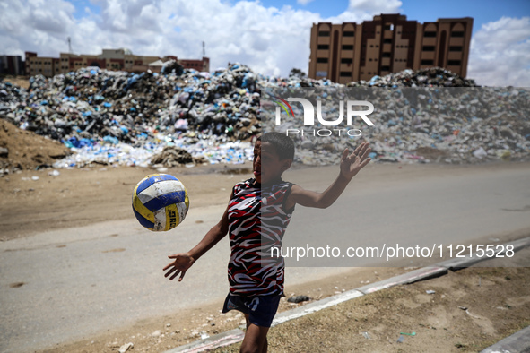 A Palestinian boy is playing next to piles of garbage amid the ongoing conflict in Gaza between Israel and Hamas in Deir Al-Balah, in the ce...