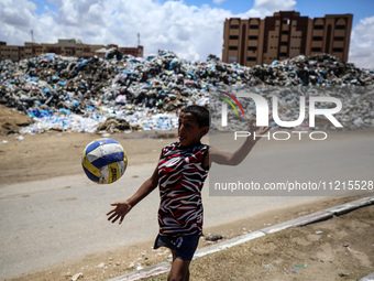 A Palestinian boy is playing next to piles of garbage amid the ongoing conflict in Gaza between Israel and Hamas in Deir Al-Balah, in the ce...