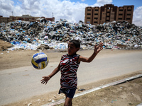 A Palestinian boy is playing next to piles of garbage amid the ongoing conflict in Gaza between Israel and Hamas in Deir Al-Balah, in the ce...