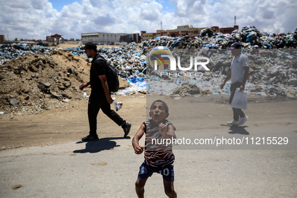 A Palestinian boy is playing next to piles of garbage amid the ongoing conflict in Gaza between Israel and Hamas in Deir Al-Balah, in the ce...