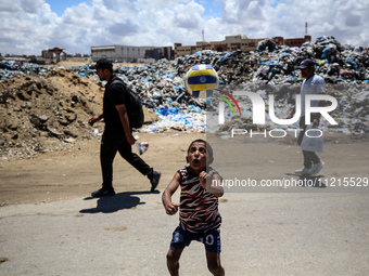 A Palestinian boy is playing next to piles of garbage amid the ongoing conflict in Gaza between Israel and Hamas in Deir Al-Balah, in the ce...