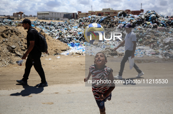 A Palestinian boy is playing next to piles of garbage amid the ongoing conflict in Gaza between Israel and Hamas in Deir Al-Balah, in the ce...