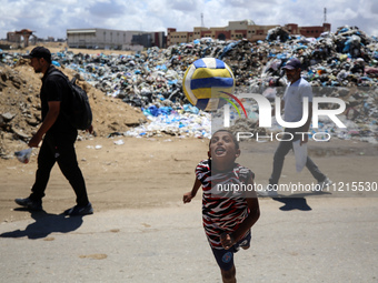 A Palestinian boy is playing next to piles of garbage amid the ongoing conflict in Gaza between Israel and Hamas in Deir Al-Balah, in the ce...