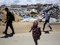 A Palestinian boy is playing next to piles of garbage amid the ongoing conflict in Gaza between Israel and Hamas in Deir Al-Balah, in the ce...