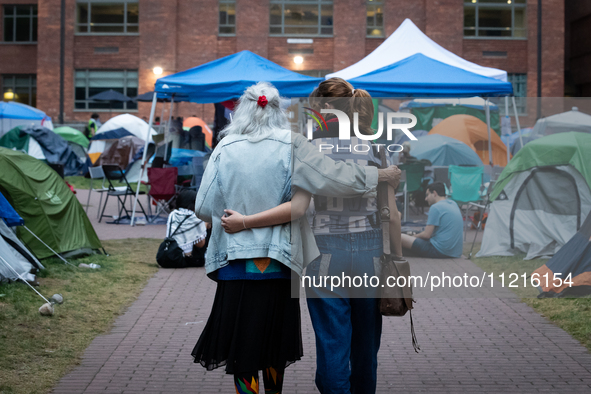 A Holocaust survivor and a demonstrator walk arm-in-arm through the Gaza solidarity encampment at George Washington University, now in its 1...