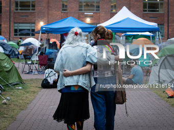 A Holocaust survivor and a demonstrator walk arm-in-arm through the Gaza solidarity encampment at George Washington University, now in its 1...