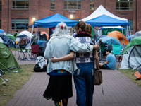 A Holocaust survivor and a demonstrator walk arm-in-arm through the Gaza solidarity encampment at George Washington University, now in its 1...