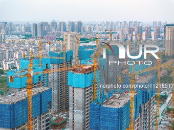 Workers are working at the real estate construction site of a resettlement housing project along the Beijing-Hangzhou Grand Canal in Huai'an...