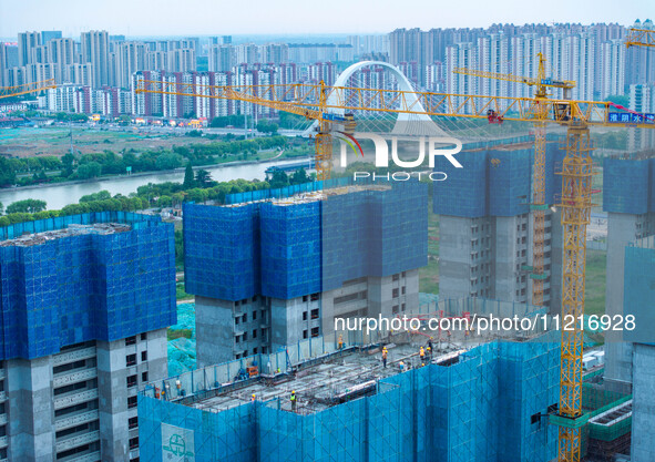 Workers are working at the real estate construction site of a resettlement housing project along the Beijing-Hangzhou Grand Canal in Huai'an...