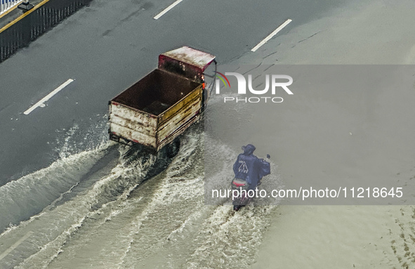 Cars are wading through a flooded road amid an orange rainstorm alert in Nanning, Guangxi Province, China, on May 8, 2024. 