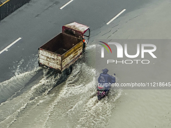 Cars are wading through a flooded road amid an orange rainstorm alert in Nanning, Guangxi Province, China, on May 8, 2024. (